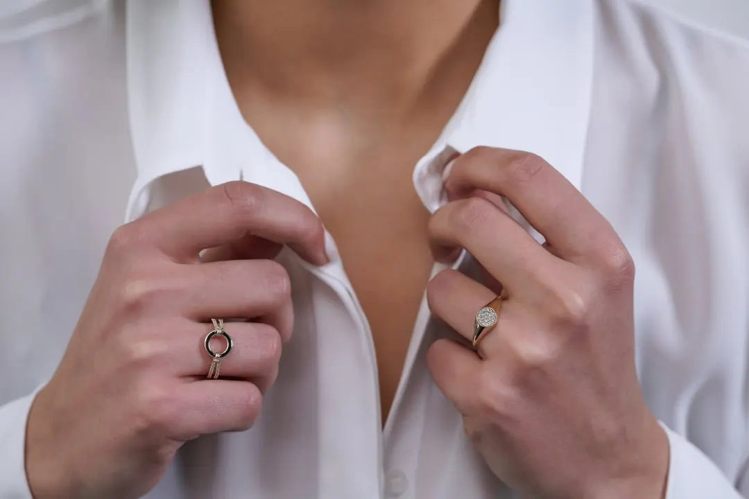 Hands with a gold signet ring adjusting a white shirt collar for a polished look