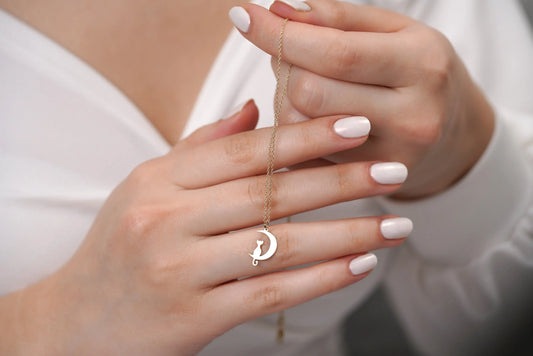 Delicate 14K Solid Gold Moon Necklace pendant held between fingers with white nail polish