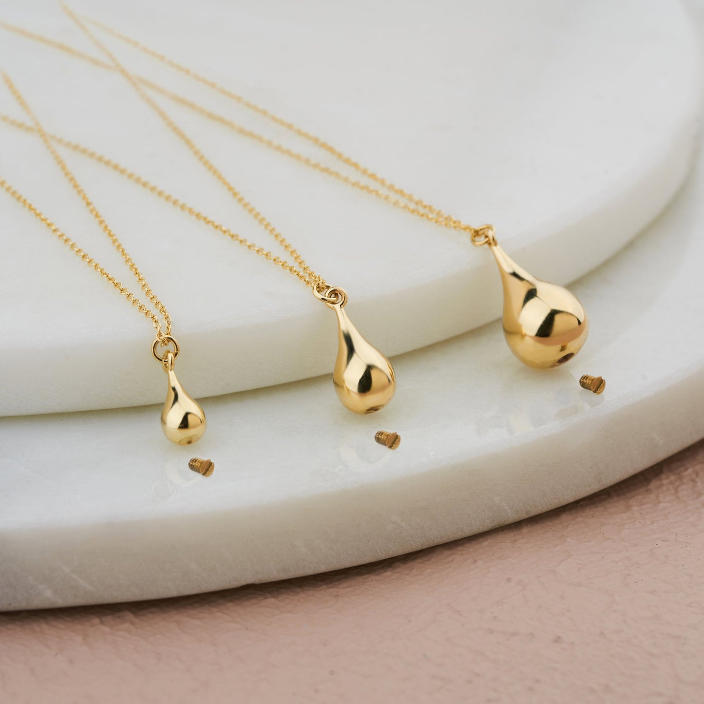 Gold teardrop-shaped pendants on delicate chains for a personalized cremation urn necklace