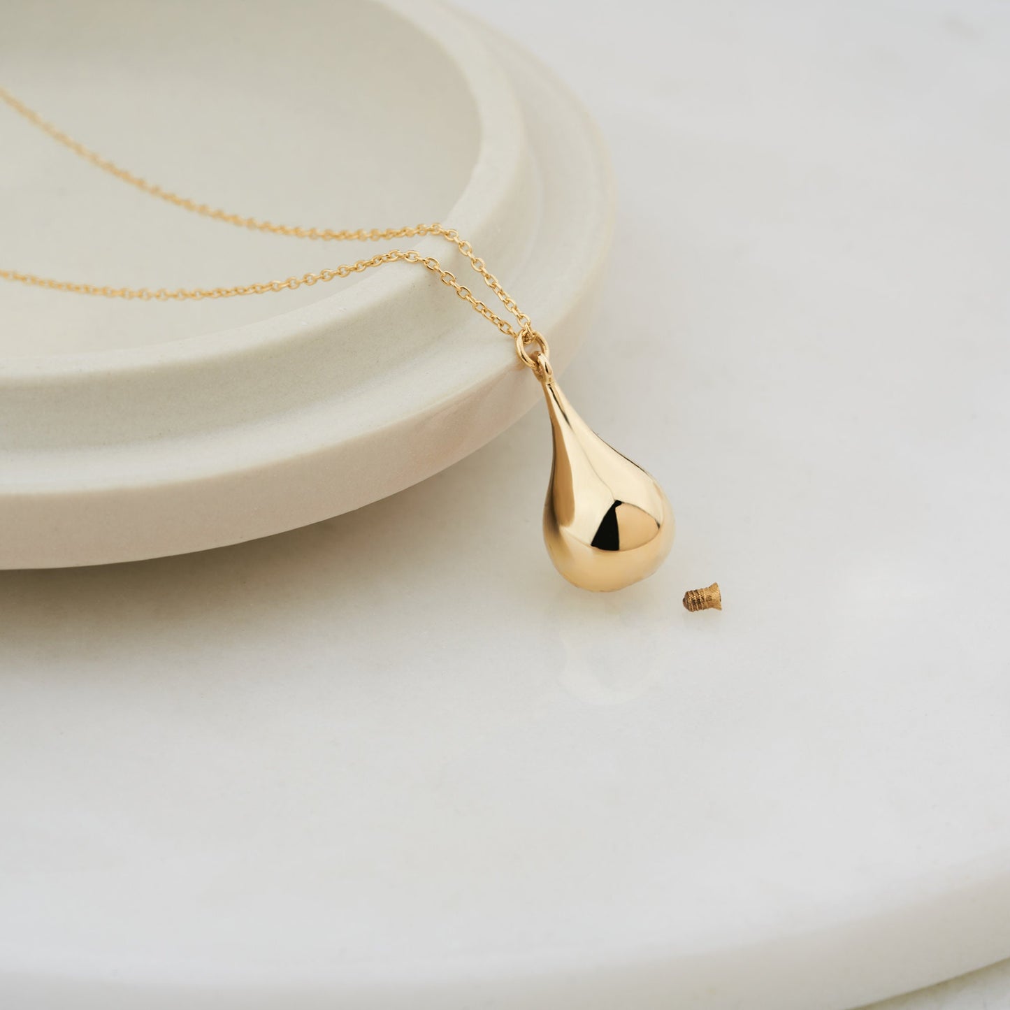 Gold teardrop cremation urn pendant on a delicate chain necklace for personalization