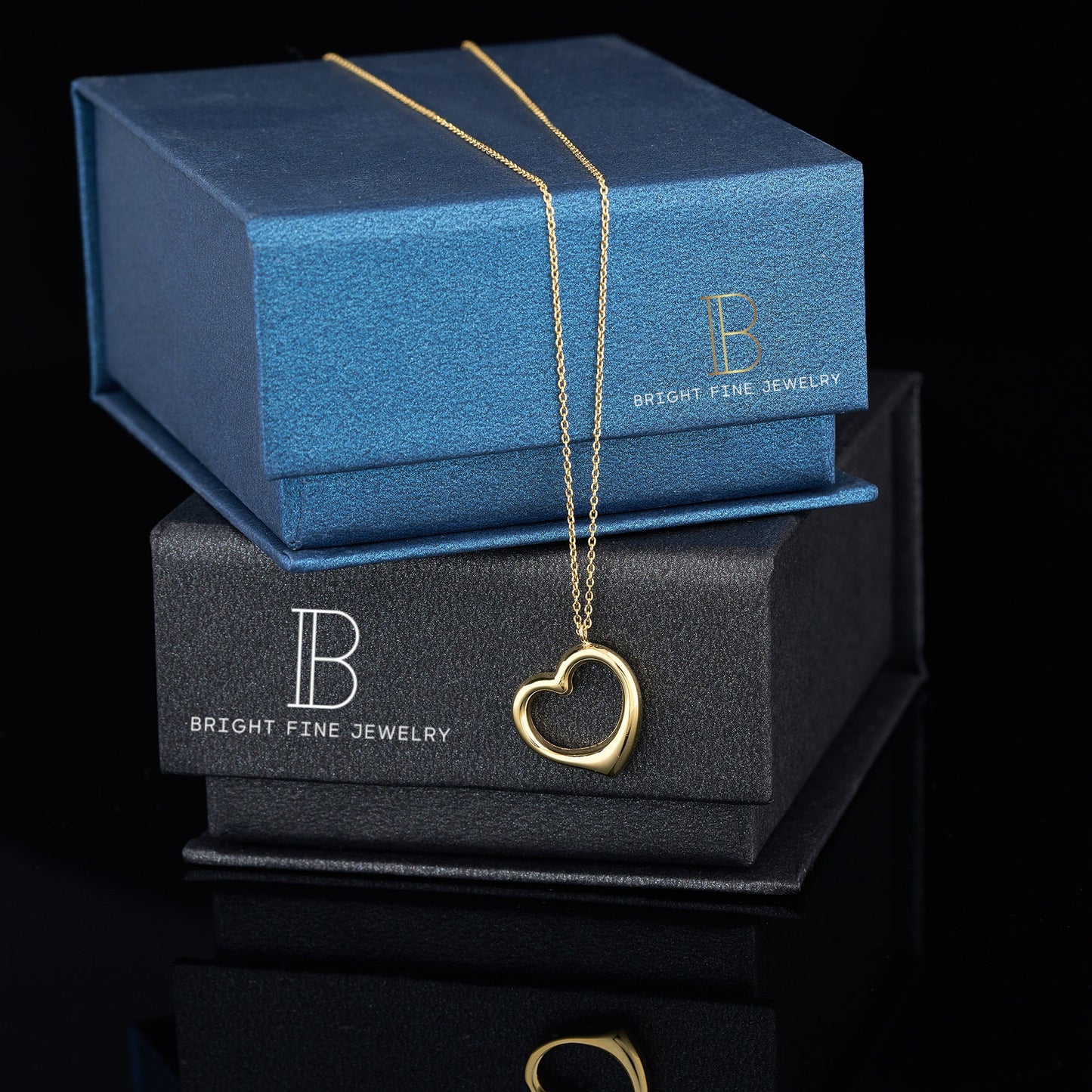 Gold heart pendant necklace on jewelry boxes, showcasing 14K solid gold elegance