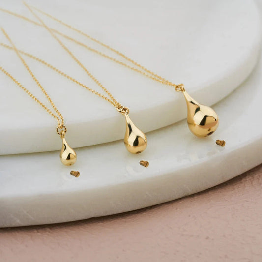 Three gold tear drop pendants on delicate chains featured in a 14K Gold Tear Drop Urn Necklace