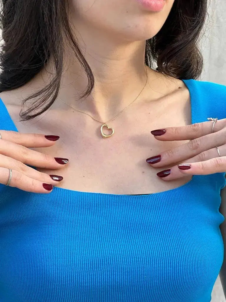 Delicate 14K solid gold heart pendant necklace worn with a bright blue top