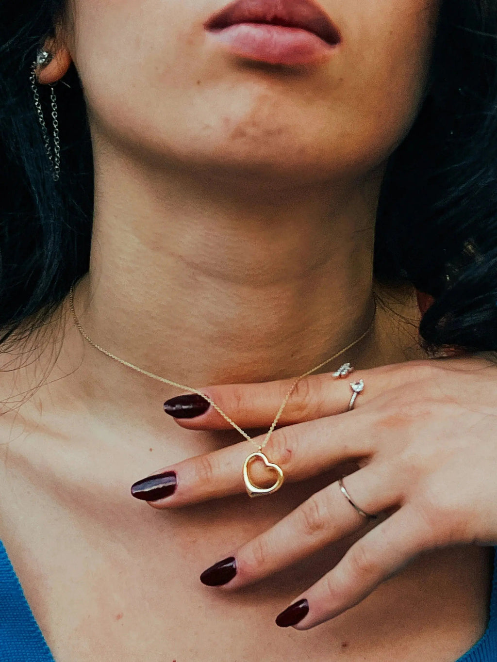 Delicate heart-shaped solid gold necklace with burgundy manicured nails featured