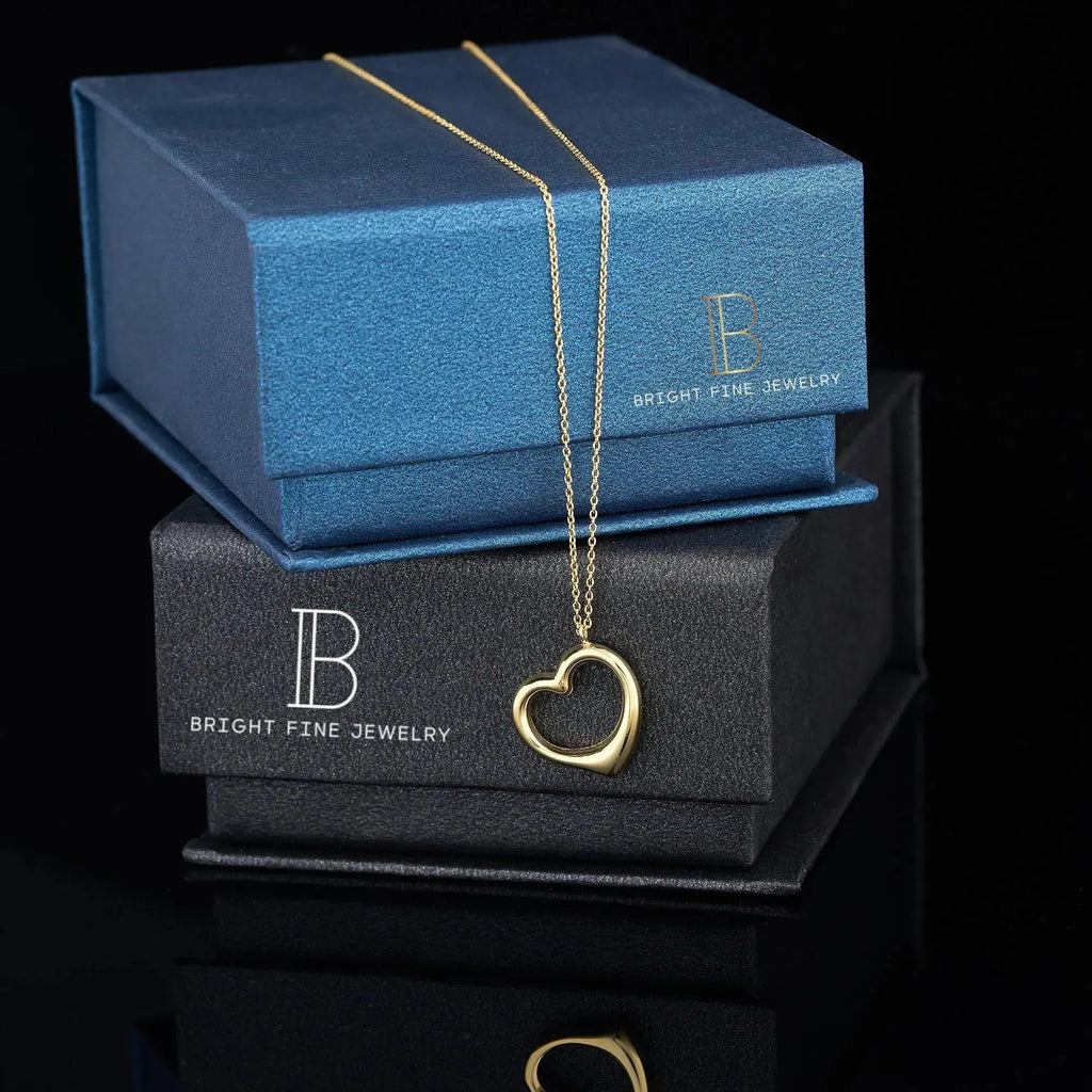 Gold heart pendant necklace on jewelry boxes, showcasing 14K solid gold elegance