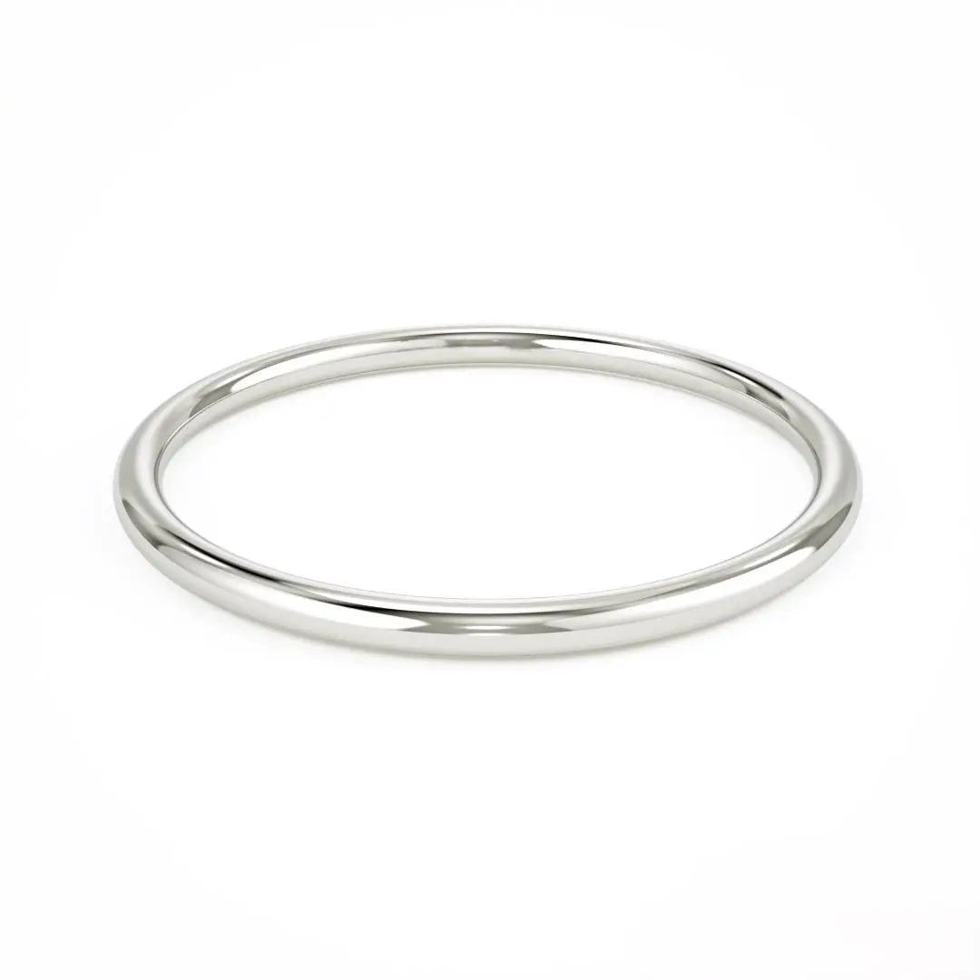 Simple silver bangle bracelet with a smooth surface beside an Elegant 14k Gold Wedding Band