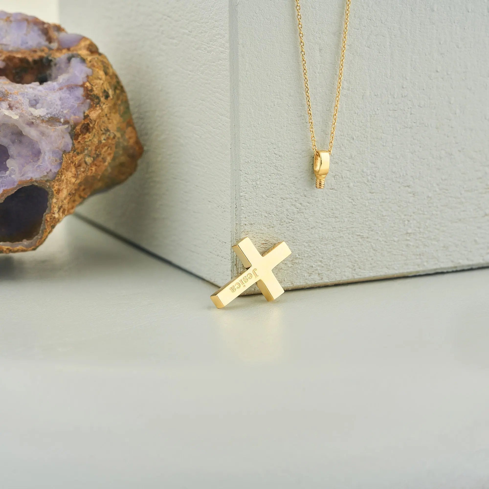Gold cross pendant on a delicate chain of a personalized cremation urn necklace