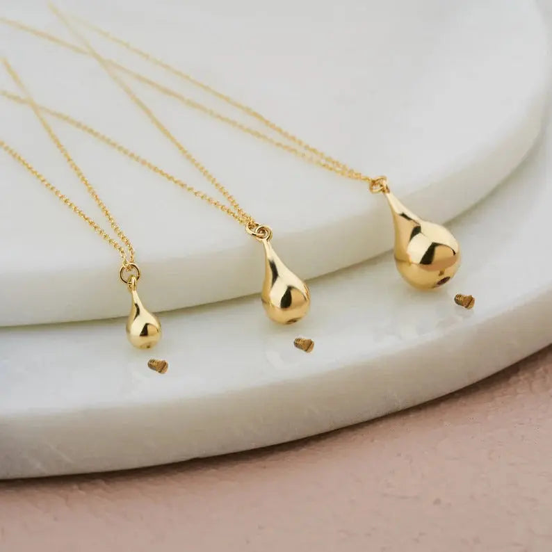 Three gold tear drop pendants on delicate chains featured in a 14K Gold Tear Drop Urn Necklace